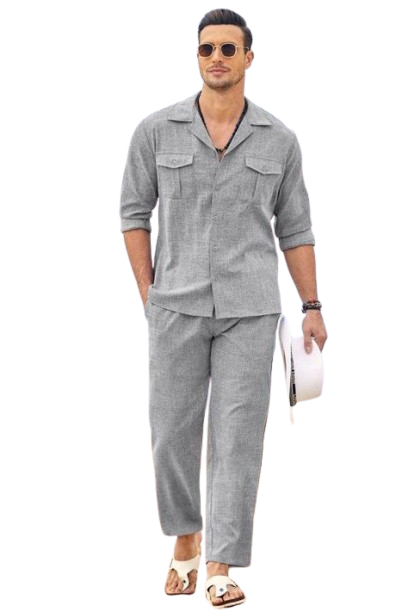 Man in gray linen outfit walking on beach with sunglasses.